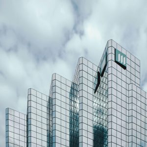 Contemporary skyscraper with mirrored glass reflecting clouds, showcasing urban architecture.